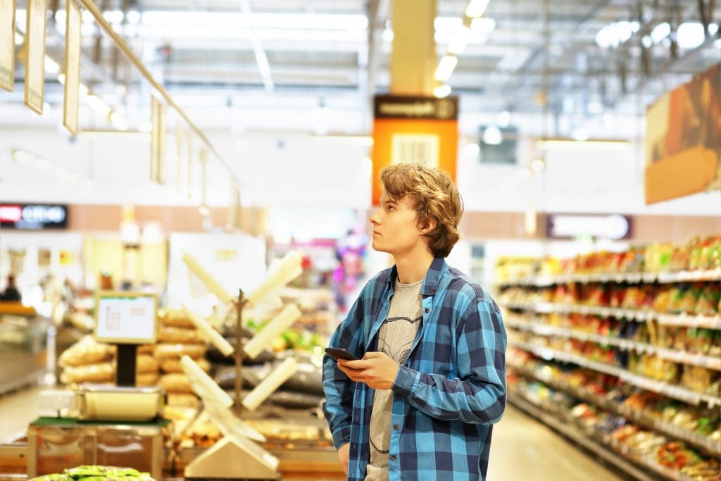 Life skills for teens: Teenager shopping in supermarket, reading product information